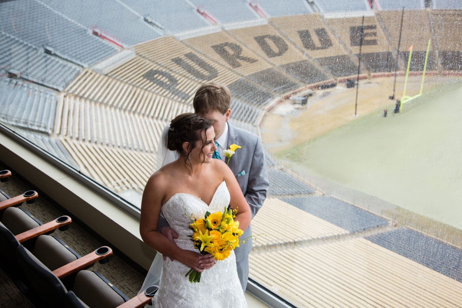 bride and groom pose at purdue university ross ade stadium